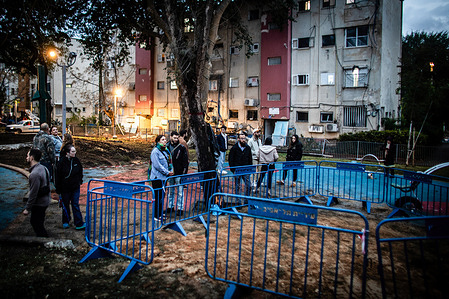 Israeli residents stand next to a covered crater following a Houthi ballistic missile. A Houthi rebel missile struck Tel Aviv early Saturday after failing interception, marking a rare occurrence over the city. The attack followed Israeli airstrikes in Gaza that killed seven children in Jabaliya on Friday, amid ongoing regional conflict. Yemen's Houthi forces claimed responsibility, stating they launched a "Palestine 2" hypersonic ballistic missile targeting an Israeli military site in Jaffa.