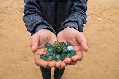A children seen showing small balls while playing the 'marbles', one of the most popular Palestinian game in the Jabalya refugee camp, Tal al-Zaatar area in the northern Gaza Strip.
