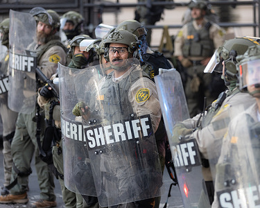 Los Angeles County Sheriff’s deputies in tactical gear stand in formation behind riot shields in preparation for crowd control measures during an anti-ICE protest. A demonstration staged as part of a national day of action drew hundreds of protesters who marched against ICE and police violence in downtown Los Angeles