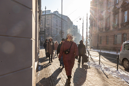 People wearing puffer jackets walk on landmark Planty Park in the city center as the temperatures drop below zero.
