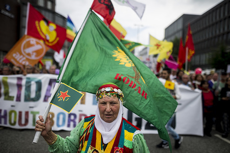 A woman is walking in front of the Demonstration. Under the motto "Solidarity without borders instead of G20", around 76,000 people demonstrated peacefully against the G20 summit. At the G20 Summit in Hamburg, the most important industrialized and emerging countries meet and serve as a forum for problems of the international economic and financial system.