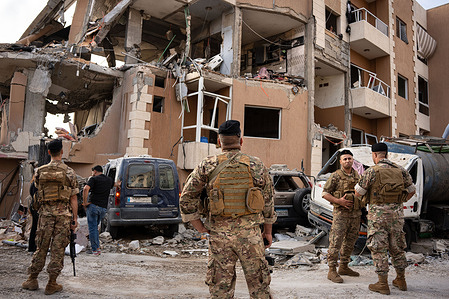 Lebanese military personnel stand in front of a building bombed by Israel. An Israeli bombing in Ras-el-Nabaa, Beirut, Lebanon, has left at least 22 people killed.