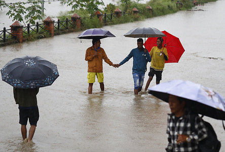People walk through flooded homes as the Nepal Army uses loudspeakers to urge residents to evacuate immediately after continuous heavy rainfall on the outskirts of Teku. The Government of Nepal has announced a two-day public holiday starting Sunday due to severe weather forecasts and the rising risk of floods and landslides across the country.