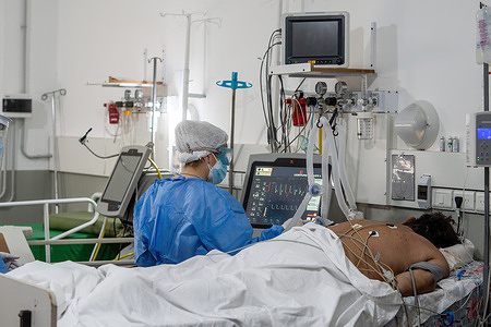 A nurse wearing a Personal Protective Equipment suite (PPE) checks on an infected patient laying inside the covid-19 intensive care unit (ICU) in Hospital San Martin.The second wave of COVID-19 is hitting hard, with the country reaching record of deaths and contagions, the health system of the Province of Santa Fe has 90% of occupation, and both Federal and Provincial Governments have placed strict restrictions to try to control de virus spread.