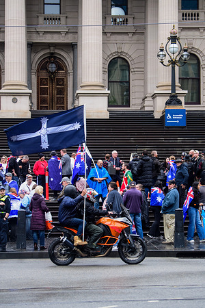Two protesters ride past Victoria's Parliament House on a motorcycle flying the Eureka flag after an anti-immigration rally. Around one hundred protesters gathered in heavy rain on the steps of Parliament House in Melbourne during a peaceful rally calling for the “sacking of the government” following the Bondi attack. The demonstration included anti-immigration activists, One Nation supporters, and organisers who previously rose to prominence during Melbourne’s anti-lockdown protests. Participants displayed Australian and Israeli flags and accused state and federal governments of policy failures, while speakers addressed the crowd amid persistent rainfall blaming the federal government for the Bondi attack. Police maintained a large presence throughout the rally.