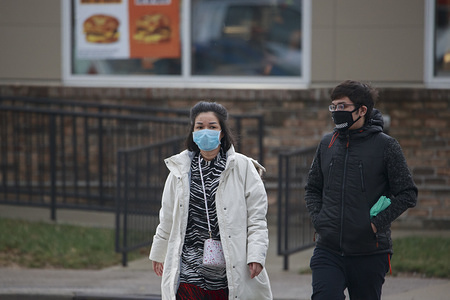 BLOOMINGTON, UNITED STATES - MARCH 12, 2020: A man and woman wearing face masks as a precaution against the spread of Coronavirus walk past the CVS pharmacy in Bloomington.
No cases have been confirmed locally yet, but area high schools announced their closure for several weeks to slow down the spread of the virus.