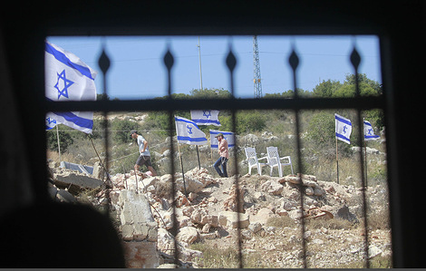 Jewish settlers erect Israeli flags near the window of a Palestinian home and raise them on confiscated Palestinian land in the village of Bruqin, west of Salfit, in the northern West Bank. Jewish settlers launched fierce attacks on the Palestinian village of Bruqin, burning several homes and cars and seizing land.