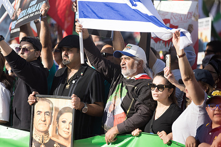 Protesters raise Iranian flags and a portrait of Iran’s former royal family during a demonstration in support of Iran’s revolution at Persian Square in Westwood, at the Los Angeles Stands with Iran’s Revolution rally.