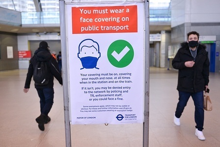 Commuters seen walking past a Wear Face Covering poster at Stratford Station.
Face coverings in England have become compulsory again in public transport, in fear of the new Covid-19 variant, Omicron.