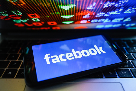 In this photo illustration, a Facebook logo is displayed on a smartphone with stock market percentages on the background.