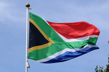 The South African national flag seen fluttering in the wind on a flagpole.