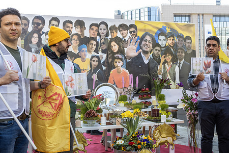 Supporters of the National Council of Resistance of Iran (NCRI), the Iranian resistance, stand beside a Nowruz display honoring victims of repression in Iran during the rally. More than 1,000 Iranians and supporters of the National Council of Resistance of Iran (NCRI) gathered at Place Schuman in Belgium, during the EU summit, calling for regime change by the Iranian people, urging recognition of a provisional government based on Maryam Rajavi’s Ten-Point Plan, and marking the eve of Nowruz as a symbol of democratic change in Iran.