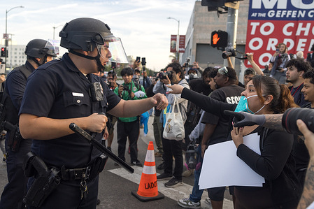 An officer holds the line as protestors advance after police declare unlawful assembly in Downtown LA during the No Kings rally.