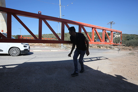 A Palestinian crosses the iron gates after the Israeli occupation forces sealed off villages south of the city of Tulkarm. The closure followed an explosion in an Israeli military jeep that injured two Israeli soldiers, prompting the army to impose a siege on the city of Tulkarm and its villages.