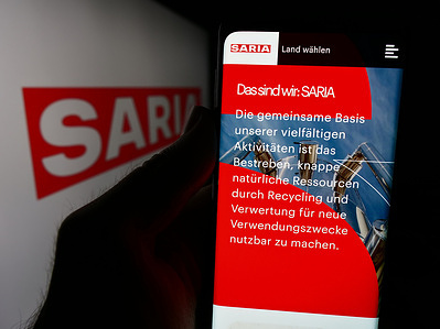 In this photo illustration, a hand holds a smartphone with the webpage of German food service company Saria AS GmbH Co. KG in front of logo.