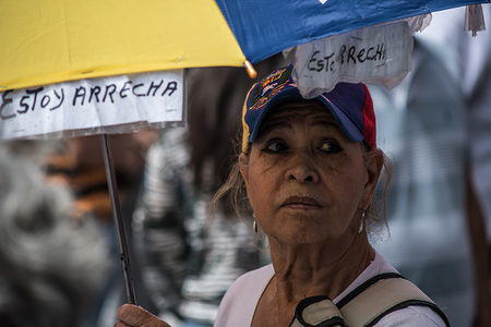 A woman seen holding an umbrella displaying the flag of venezuela during a protest in front of UN headquarter in Caracas.
The ‘Broad Front for a Free Venezuela’ (FAVL) carries out its first street action by concentrating front of the UN headquarters in Caracas to protest against the presidential elections on May 20.
From 10:30 am the members of the ‘Frente Amplio’ and demonstrators who support their cause began to concentrate, to support this request addressed to the United Nations. Congresswoman Delsa Solórzano and Apucv's president, Víctor Márquez, entered the headquarters of the UNDP (United Nations Development Program) to deliver the document of the grouping of civil society and opposition parties.
An other march is expected for next Saturday on March 17, 2018.