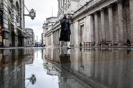 A man walks in his rain jacket in central London in front of the Bank of England building as inflation in the UK rose unexpectedly.