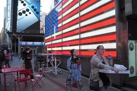 People walk past a lighting installation of the American flag in Times Square, Manhattan, New York City.