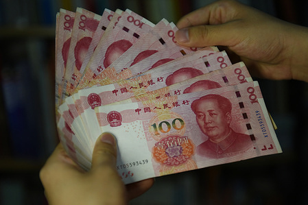 In this photo illustration a man counts 100 RMB notes.
In recent years, China has clamped down on shadow banking, concerned about the hidden risks in the high volume of complex and potentially risky loans in the sector. As a weakening economy puts pressure on businesses and individuals, authorities fear shadow lending and illegal loans might surge.