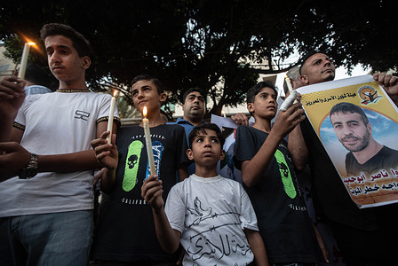 A Palestinian child holds a lit candle during a demonstration calling for Israel to release prisoner Nasser Abu Hamed, who suffers from lung cancer, from Israeli prisons. The protest took place in front of the International Committee of the Red Cross building in Gaza City.