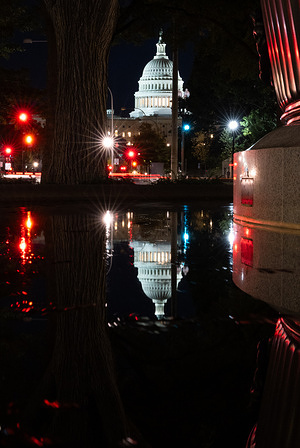 The U.S. Capitol dome is reflected in a fountain.