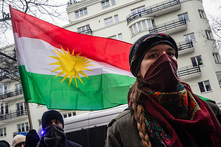 A masked protester is seen in front of a Kurdish flag during a demonstration. On the afternoon of the 30th of January, human rights protesters gather at the American embassy in Warsaw on behalf of the Kurdish community in response to the ongoing acts of violence against civilians in the Sheikh Maqsud and Al-Ashrafiya districts of Aleppo. These districts have historically been inhabited by the Kurdish community and have once again become targets of collective punishment against civilians, including shelling and blockades. After speeches, the protesters march together to the Polish Ministry of Foreign Affairs.