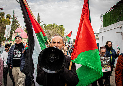 Israeli and Palestinian protestors wave Palestinian flags during a demonstration at the Sheikh Jarrah neighborhood in Jerusalem. Israeli police officers ignored activists marching and waving Palestinian flags in defiance of the order issued by Israel's National Security Minister Itamar Ben Gvir for police to remove and ban Palestinian flags from public places.