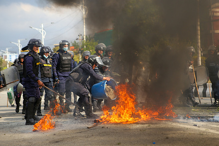 Police officers attempt to clear a burning tyre set alight by supporters of former Prime Minister K. P. Sharma Oli during a protest demanding his release after his arrest over alleged involvement in a deadly crackdown on protests in September 2025.