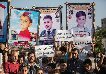 Palestinians together with children hold placards with messages and pictures of the children killed, calling for children's protection during a vigil at the site where 5 children of the Najm family were killed in the latest Israeli attack on Gaza. Palestinians hold a vigil at the Fallujah cemetery near Jabalia refugee camp in the northern Gaza Strip. The vigil comes in the wake of Israeli officials' recognition of the killing of five children in an Israeli air strike on the Fallujah cemetery, west of Jabalia refugee camp in the northern Gaza Strip.