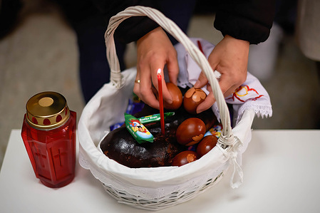 An Orthodox woman places Easter eggs in a basket where they will be blessed by priest Igor Tatarintsev, in celebration of Christ's resurrection. Orthodox Easter celebrated in France, in the Orthodox Parish Mother of God and Saint Alexander of Neva. The faithful of the Orthodox Church celebrate the resurrection of Jesus Christ, going to the Church to pray the holy rites, bringing food and drink to be blessed. It is the most important act of the Orthodox Christian Rites.