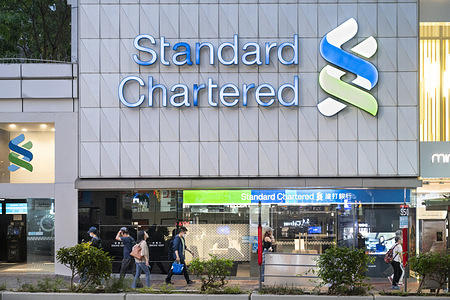 Pedestrians walk past the British multinational banking and financial services company Standard Chartered branch in Hong Kong.