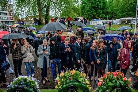 People are seen taking photos of the flowers placed after the ceremony. On this day, the whole country commemorates civilians and soldiers who perished during World War II and other conflicts. In Nijmegen, a silent procession took the streets to the "Keizer Traianusplein", where there are two monuments in remembrance of the victims of World War II. The official ceremony started with two minutes of silence, and wreaths were laid.