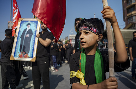 A Kashmiri Shia Muslim boy holds a religious flag while a photograph of Iranian Supreme Leader Ayatollah Syed Ali Khamenei is viewed in the background during a Muharram procession. Despite the scorching heatwave, thousands of Shia mourners participated in the Muharram procession. Muharram is the first month of the Islamic calendar and is considered one of the holiest month. Shia Muslims observe Muharram as a period of mourning in remembrance of the martyrdom of Imam Hussain, the grandson of the Prophet Muhammad (PBUH). Imam Hussain was martyred on the 10th day of Muharram, known as Ashura, during the Battle of Karbala in 680 AD.