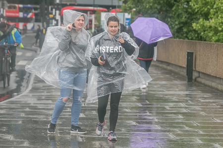 A Pedestrian wear rain ponchos during a torrential downpours while crossing the Westminster Bridge in London.