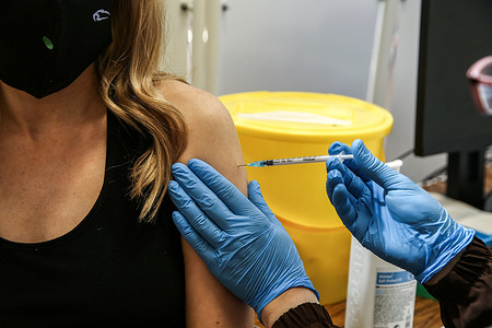 A vaccinator administers the Pfizer Covid-19 vaccine to woman at a vaccination center in London.