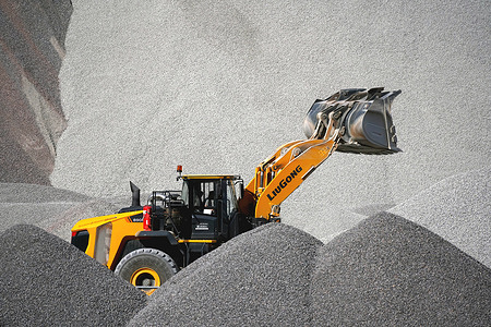 A yellow LiuGong 890H heavy-duty wheel loader moves and lifts a large bucket of crushed stone (gravel)