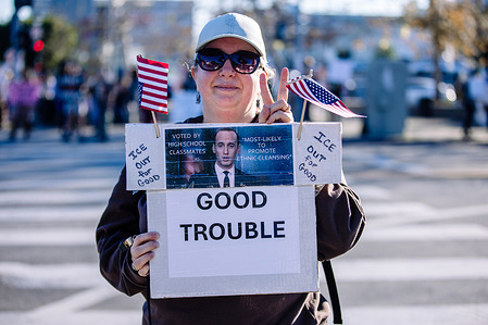 A protester displays a sign reading “GOOD TROUBLE,” with handwritten messages stating “ICE out for good,” during an anti-ICE protest in Hollywood, Los Angeles, on January 11, 2026.