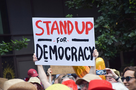 A protester holds a 'Stand up for democracy'' placard during the demonstration. Crowds gathered outside the Embassy of USA for the 'No Tyrants' protest, part of the anti-Trump 'No Kings' mass protests taking place in USA.