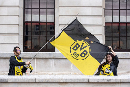 Two female Borussia Dortmund fans hold a flag on the Whitehall in London, UK. Hundreds of thousands of Borussia Dortmund and Real Madrid football or soccer fans arrived to the UEFA Champions League Final to London.