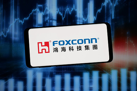 In this photo illustration, the logo of Hon Hai Precision Industry Co. Ltd. (Foxconn) is seen displayed on a smartphone in front of abstract background on computer screen.