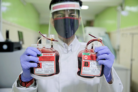 A health worker wearing protective gears holds bags of blood to be stored in a blood bank.Palang Merah Indonesia (PMI) in the city of Tangerang is experiencing shortage of blood bag stock in the midst of the Covid-19 pandemic. People's fear of Coronavirus caused a decrease in people's enthusiasm for blood donation.