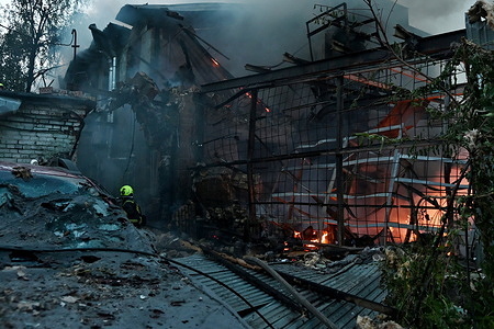 Firefighter works near the scene of a fire after a jet-powered drone struck an office building in Kyiv's Podilskyi district. The Russian army struck offices in Kyiv's Podilskyi district, destroying the facility and civilian vehicles.