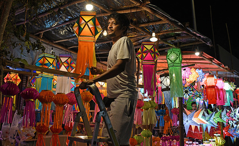 A shopkeeper stands on a ladder near lanterns displayed for sale ahead of Diwali, Hindu festival of lights at a lantern market on the streets of Mumbai. Diwali is the festival of lights celebrated by Hindus across the country. People clean their home, draw a rangoli (a traditional Indian art form where various designs are made on the floor), shop for lanterns, new clothes, sweets, and snacks. They light their homes with earthen lamps, marking the victory of light over darkness.