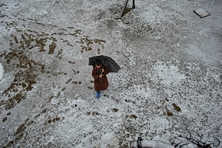 A Kashmiri boy seen walking with an umbrella through a snow covered garden during fresh snowfall in Srinagar, Indian administered Kashmir.
Fresh snowfall lashed most parts of the Kashmir Valley as the minimum temperatures rose above the freezing point. The weather men forecast improvements in weather conditions.