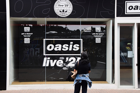 A woman takes a photo of the Oasis Live 25 pop-up store in Carnaby Street. The shop sells the reunited rock band's merchandise and records, and will be open for several days before and during their concert dates at Wembley Stadium.