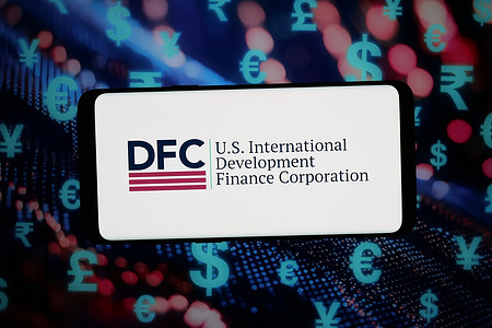 In this photo illustration, the logo of US finance development corporation DFC is displayed on a smartphone in front of abstract background on computer screen.