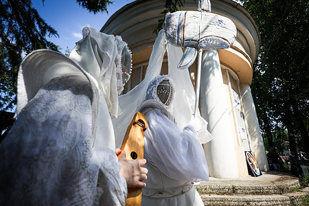 Actors of the "Sky Tramps" street theater perform in white mystical costumes and traditional woven masks during the "Kovava" festival, holding ritual bowls and interacting with textile decorations. The Kovava Street Theater Festival was held in St. Petersburg's Lopukhinsky Garden to celebrate Russia Day. The festival included performances by the "Heavenly Wanderers" theater, based on stories from Karelian, Mordvin, and Chuvash mythology. An art exhibition and plein air workshop were also organized, along with musical performances, craft workshops, and lectures on the history and study of mythical creatures in various Russian cultures.