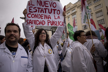 A doctor in her white coat holds a placard during a demonstration demanding better working conditions for staff in Spain's National Health System.