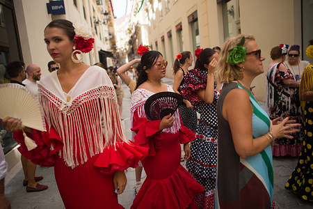 A woman dressed in flamenco costume is seen cooling off with a fan on the street as she takes part in the Malaga Fair 2025. People and tourists gathered in the city's main streets to take part in the Malaga Fair in a festive atmosphere. Over the course of a week, thousands of tourists and locals enjoy the concerts, flamenco dancing in the streets, and other activities such as the bullfighting fair and horse shows.
