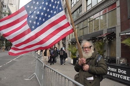 A reveler waves the American flag at the New York City Veterans Day Parade in Manhattan, New York City. The annual parade commemorating members of the United States military draws veterans, active duty military servicemen, marching bands and revelers to midtown Manhattan. This year, the parade celebrates the 250th anniversary of the U.S. military.